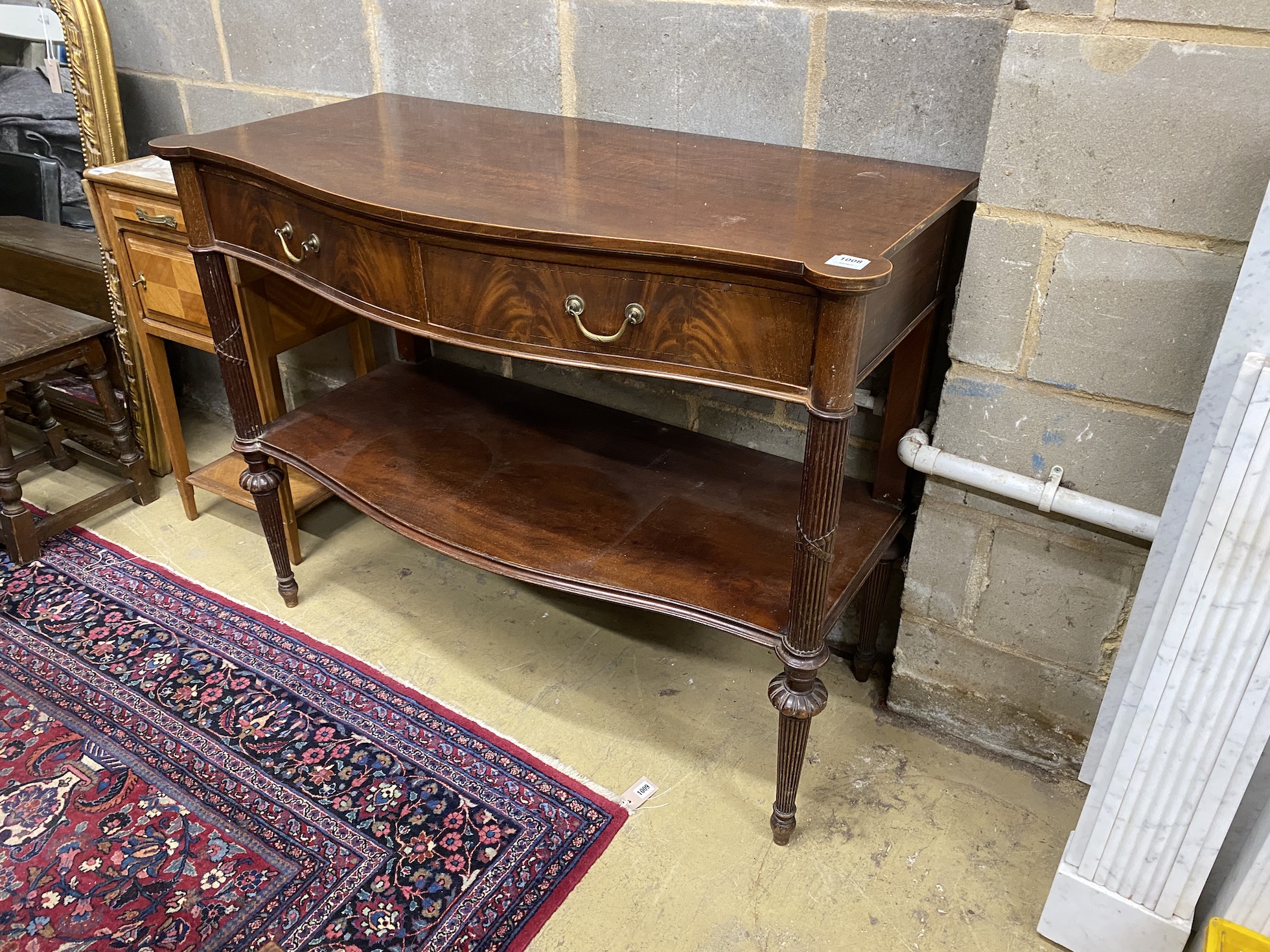 An Edwardian mahogany serpentine two tier serving table, width 122cm, depth 57cm, height 94cm